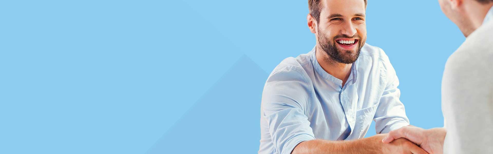 Junger, lachender Mann im hellblauen Hemd schüttelt dem Geschäftspartner die Hand